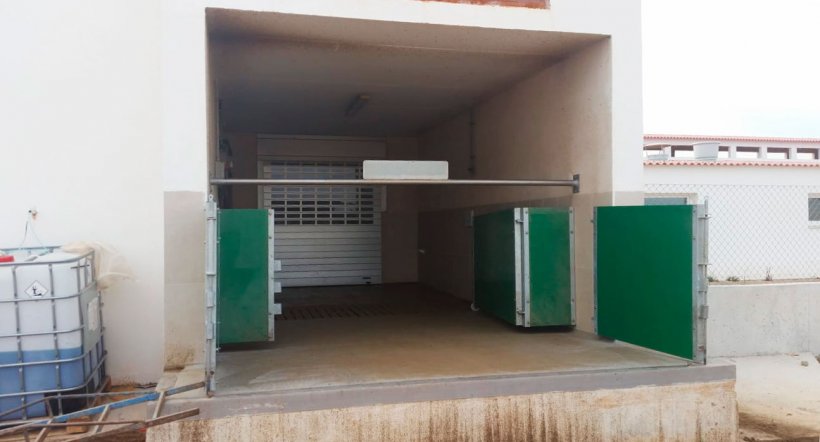Imagem 6. Local de embarque/desembarque fechado&nbsp;com portas e barra horizontal para separar fisicamente a zona suja da limpa. Cortesia de Agropecuaria Los Girasoles, Espanha.
